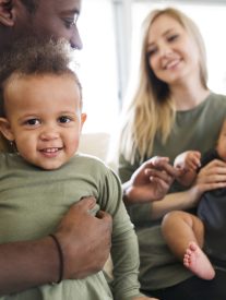 Beautiful young interracial family at home with their cute daughter and little baby son.