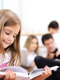 Little girl reading in home, indoor with happy family
